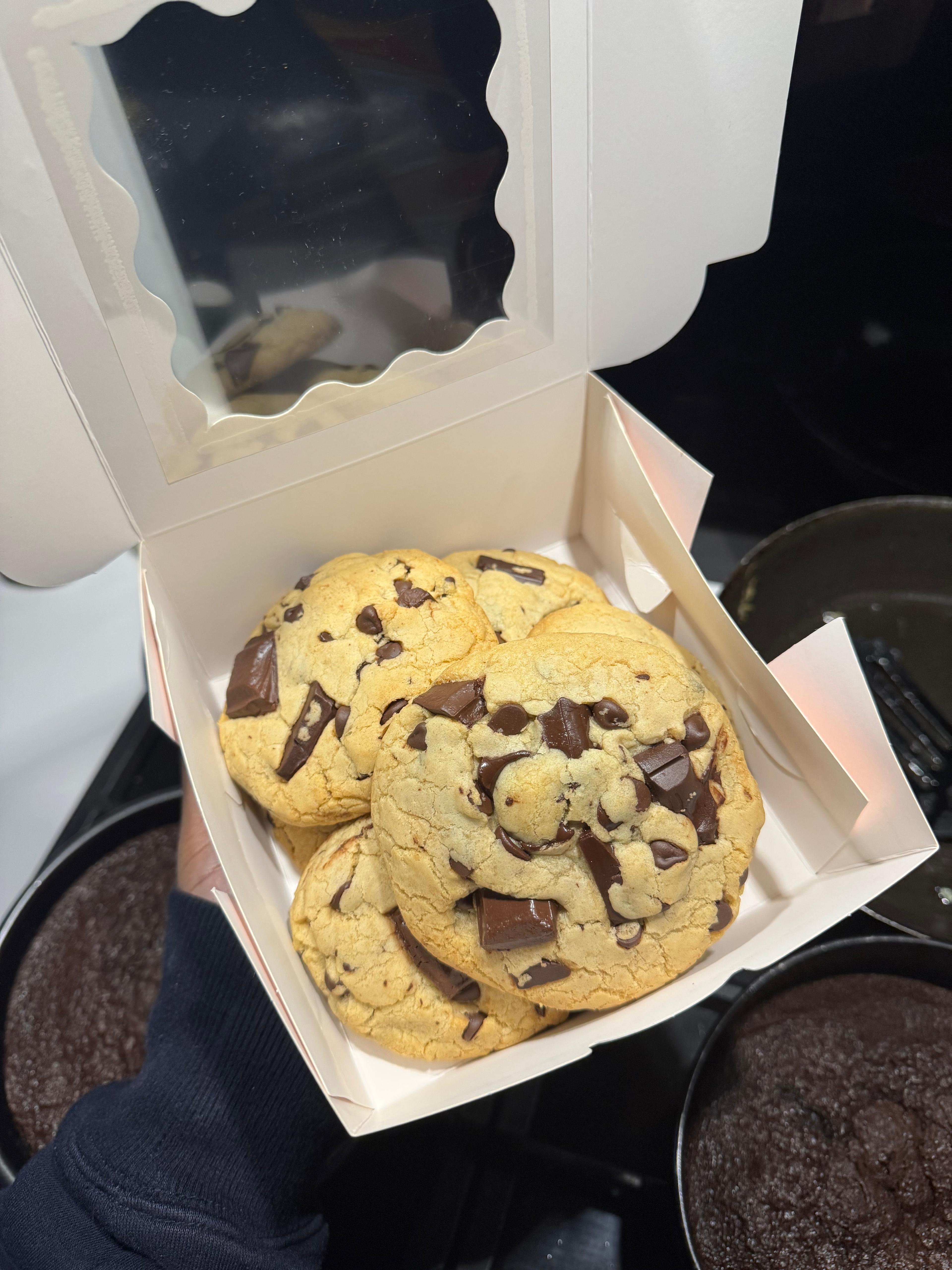 A baker's hand placing cookies into a presentation box.
